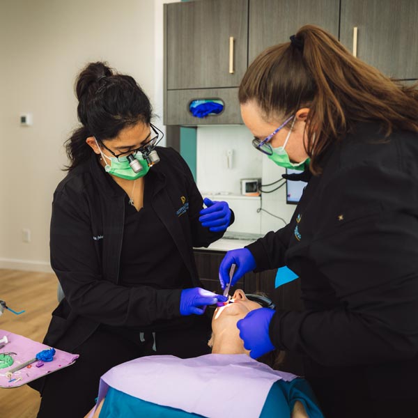 Two dental professionals are treating a patient in a modern clinic in Dripping Springs, TX
